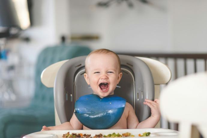 Happy baby eating solid food, representing infant formula and complementary food industry news.